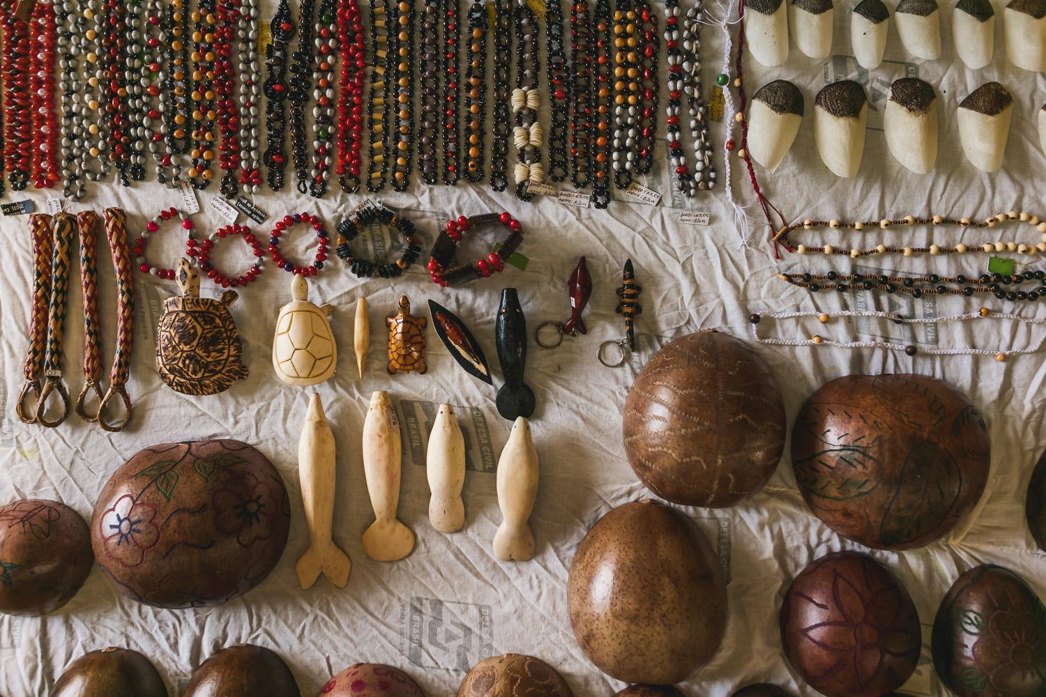 Traditional Indigenous Handicrafts from the Amazon Selection of handmade indigenous art objects such as jewelry, carved figures, and decorated gourds laid out on a white cloth