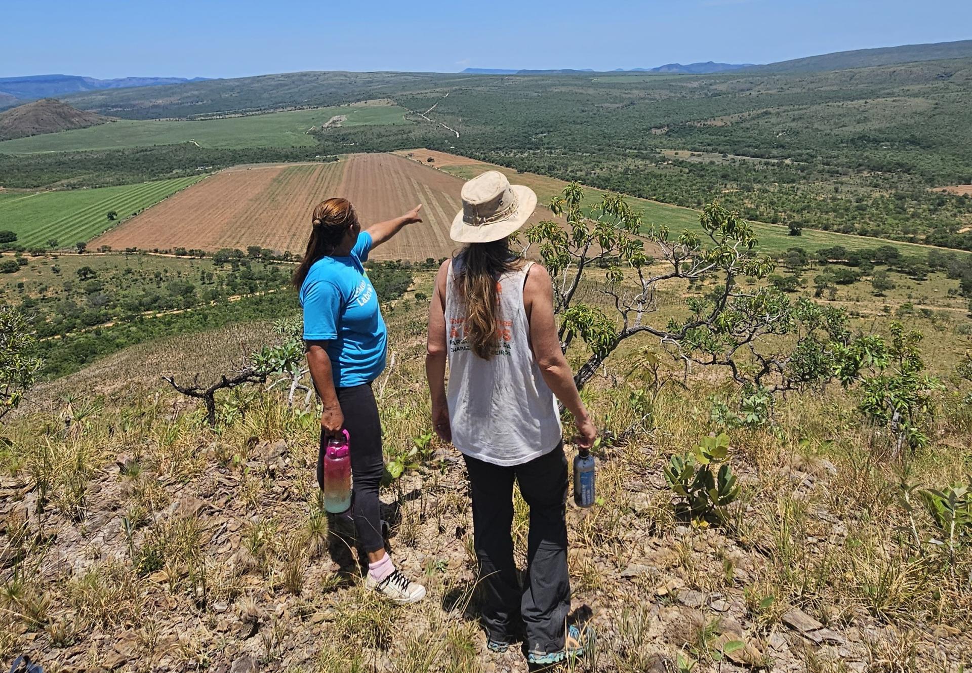 Hiking Morro da Pirâmide with views of the Cerrado – community-based tourism near Alto Paraíso Two women overlooking the green landscape of Chapada dos Veadeiros from Morro da Pirâmide – sustainable tourism in Brazil