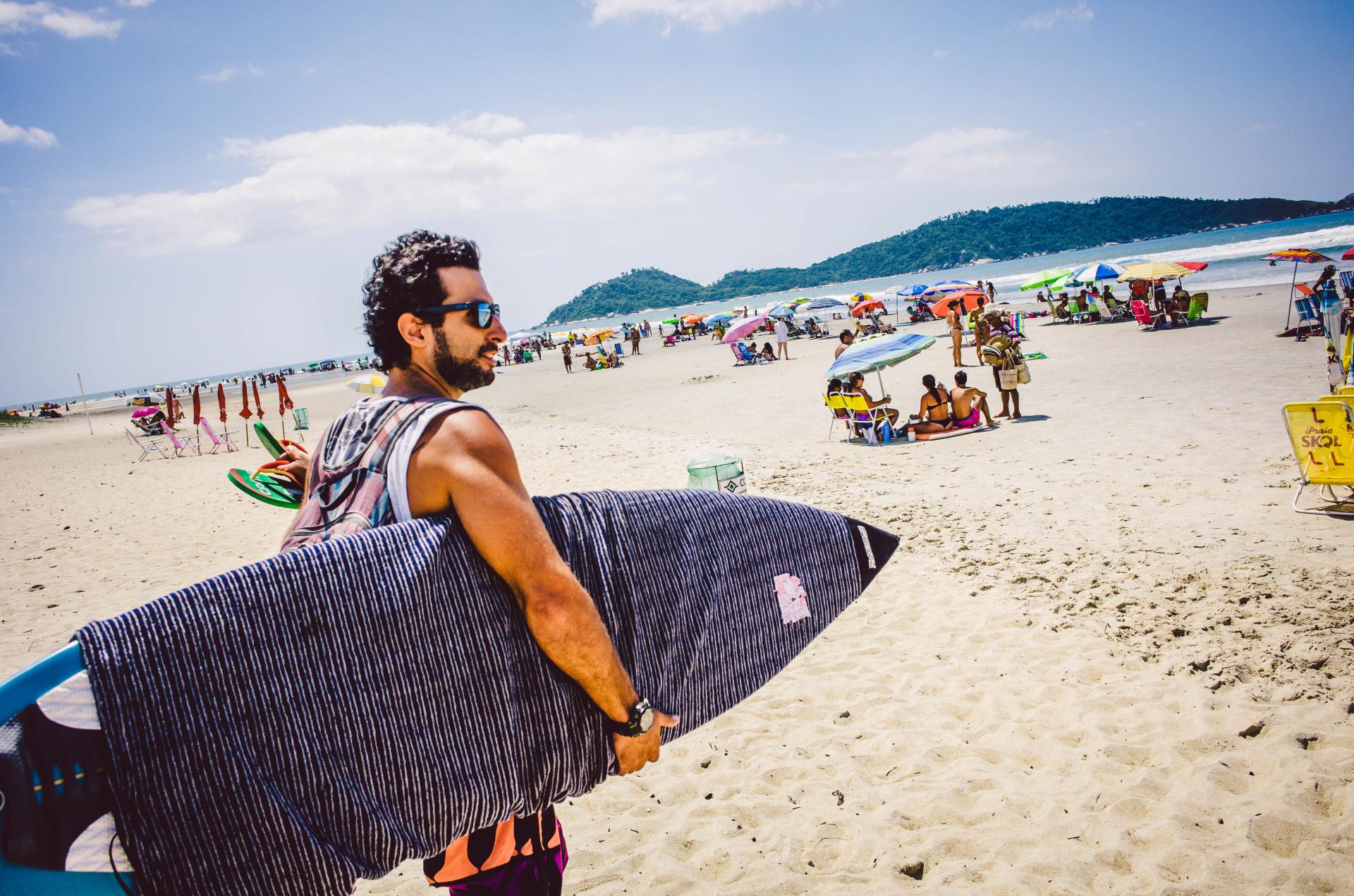 Surfer at Campeche Beach, Florianópolis – ideal spot for beginners Surfer with surfboard at Campeche Beach in Florianópolis, Brazil – sunny day and a lively beach atmosphere.