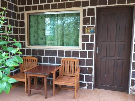 Front side of a bungalow with two seats and a table at Amazon Turtle Lodge