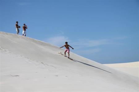 A visitor sandboarding down the dunes of Floripa