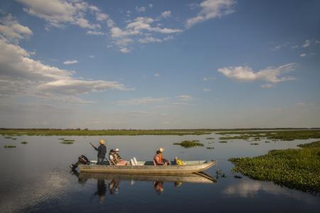 Three visitors fishing in a motorboat on a river of the North Pantanal