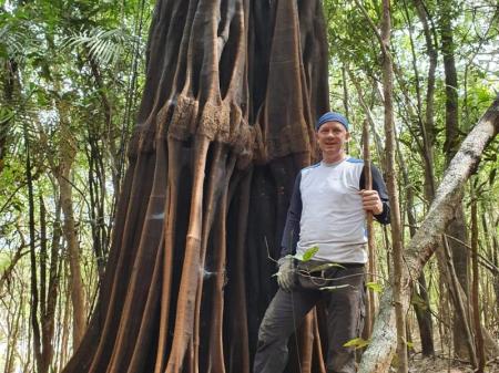 Guest posing in front of a huge trunk in the Amazon Rainforest