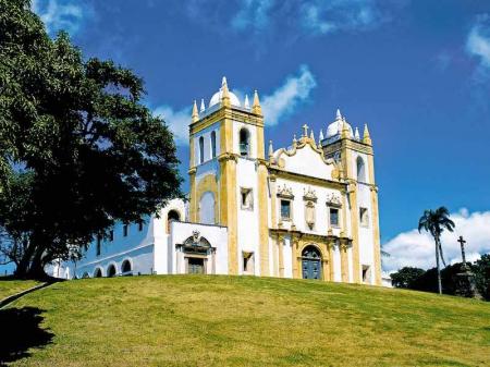 Typical white and yellow church, surounded by palm trees in Olinda, Pernambuco
