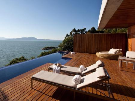 An outdoor pool with sea view and chairs at Resort Ponta dos Ganchos