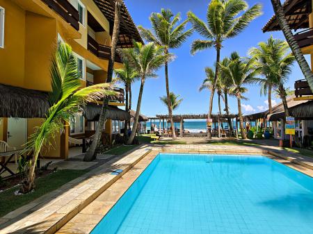 A large pool area with palm trees and sea view at Pousada Tabajuba in Porto de Galinhas, Pernambuco - Brazil