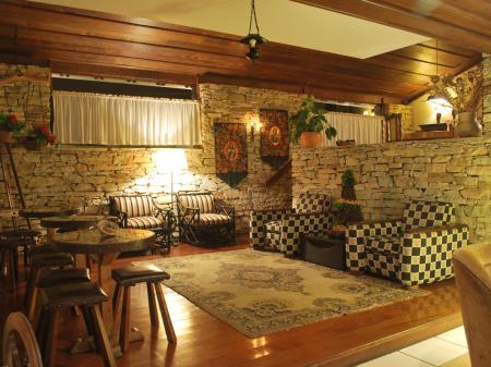 Seats and sofas in a living room with wooden floor and thick stone walls at Pousada do Arcanjo