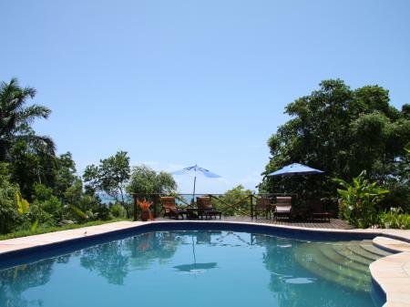 Pool area with lush green and the sea in the background, at Pousada Mangabeiras in Boipeba, Bahia - Brazil