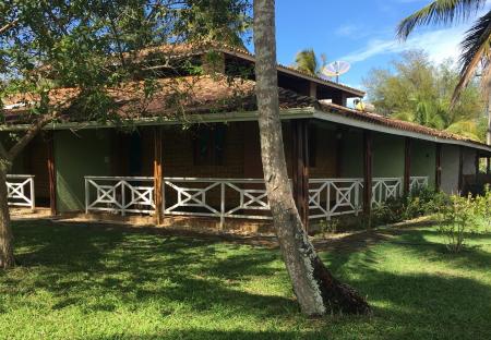 Palm trees, lush green gardens and the main building of Pousada Tapera in Itubera, Bahia