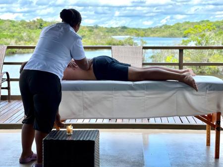 A photo of a client lying on a massage table receiving a massage on the outdoor deck of the Zaltana
